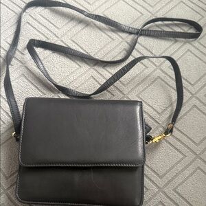 black leather crossbody shoulder bag featuring a flap closure and strap.